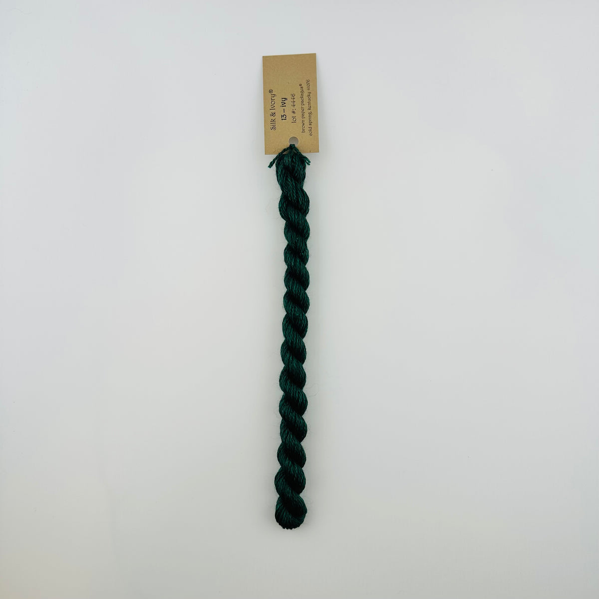 30 yard skein of silk & Ivory in the color 13 Ivy with brown tag laying flat on white background