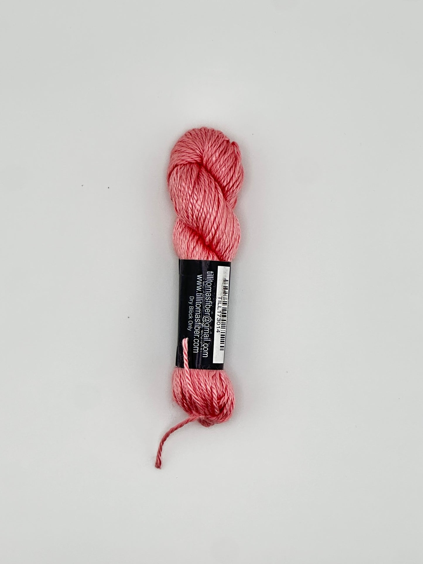 30 yard skein of Pepper Pot Silk needlepoint thread in strawberry frappe pink 014 with black and white label lying flat on white background