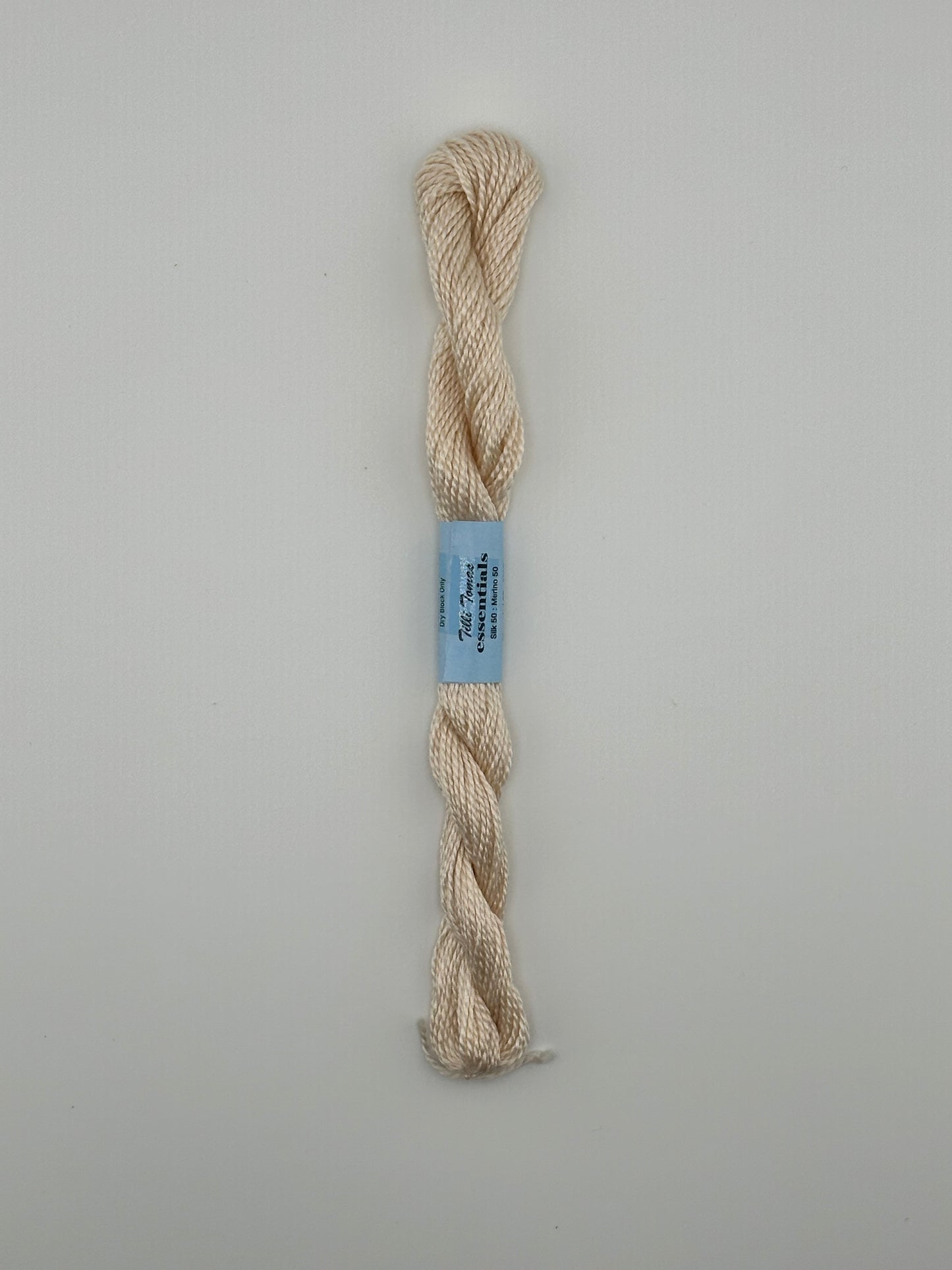 30 yard skein of essentials needlepoint thread in Sandy Toes S520 beige, with blue label lying flat on white background.