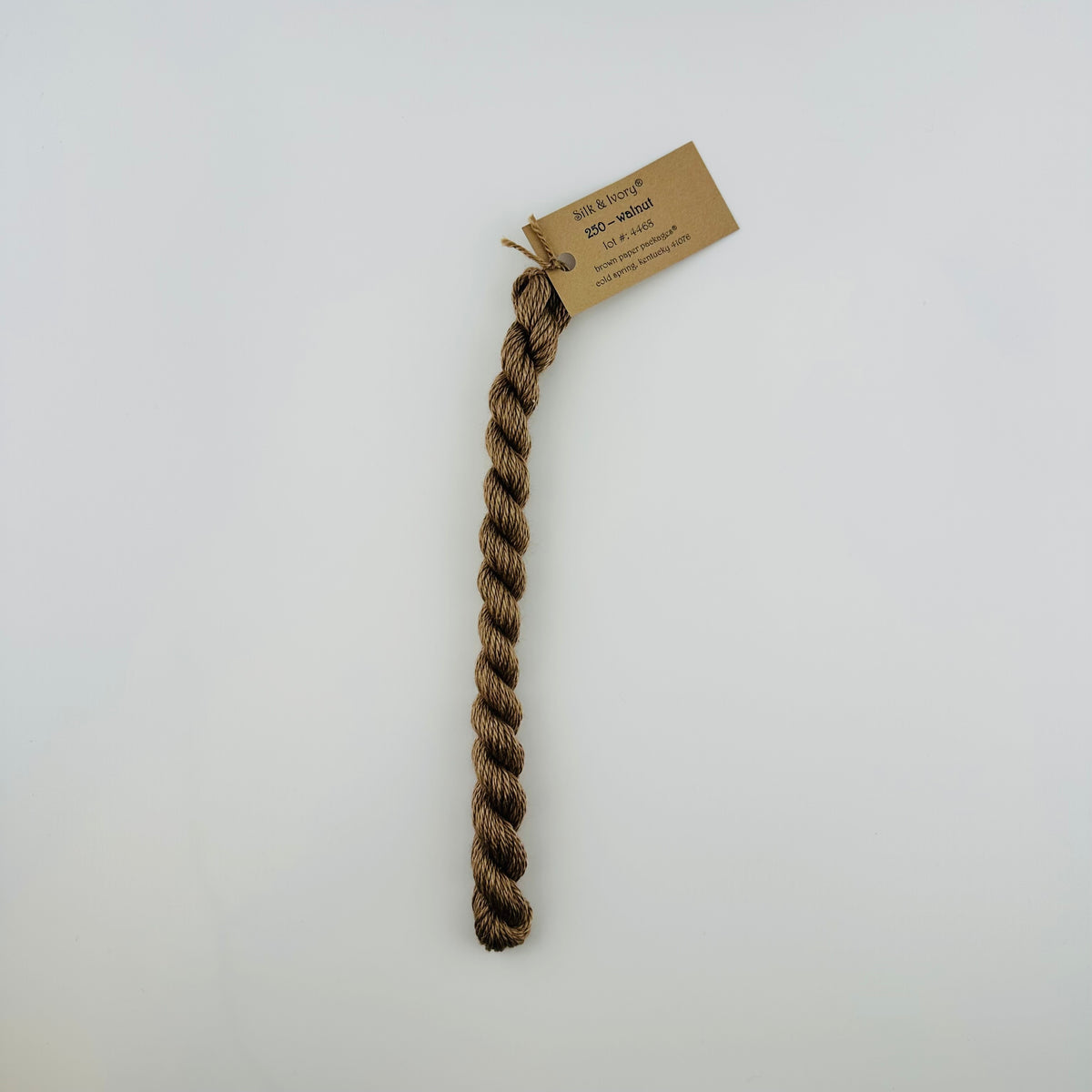 30 yard skein of silk & Ivory in the color 250 Walnut with brown tag laying flat on white background