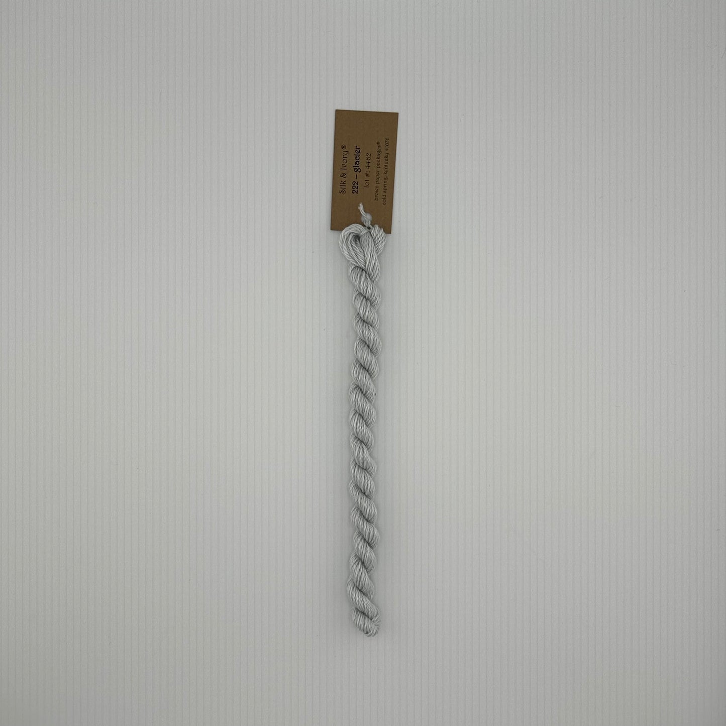 30 yard skein of silk & Ivory in the color 222 Glacier with brown tag laying flat on white background