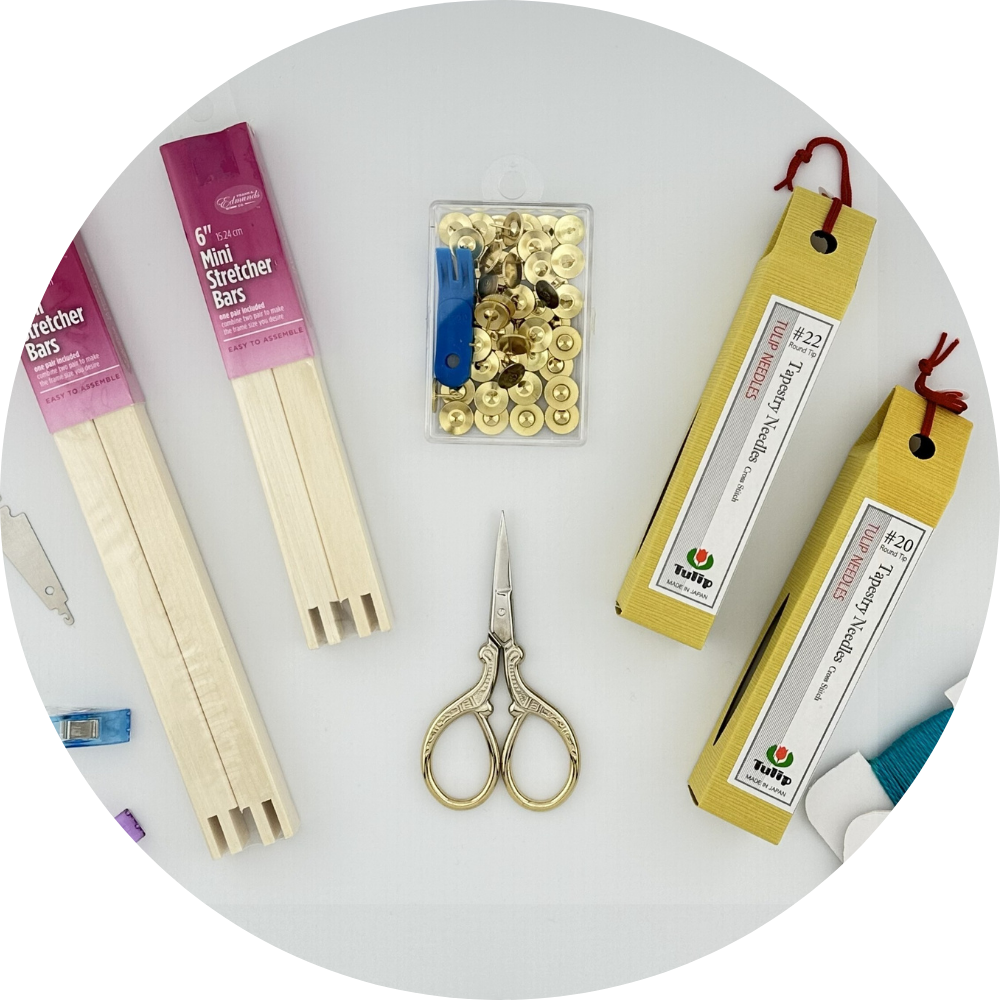 Needlepoint accessories flat lay — Tulip tapestry needles #20 & #22, mini stretcher bars, scissors, snips, brass tacks, and needle threader, at Neon Needlepoint