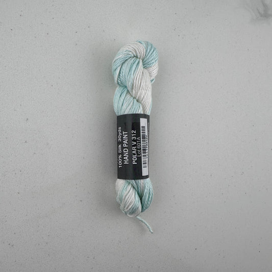 30 yard skein of Pepper Pot Silk needlepoint thread in a blue and white variegated polar v312, with black and white label lying flat on white background
