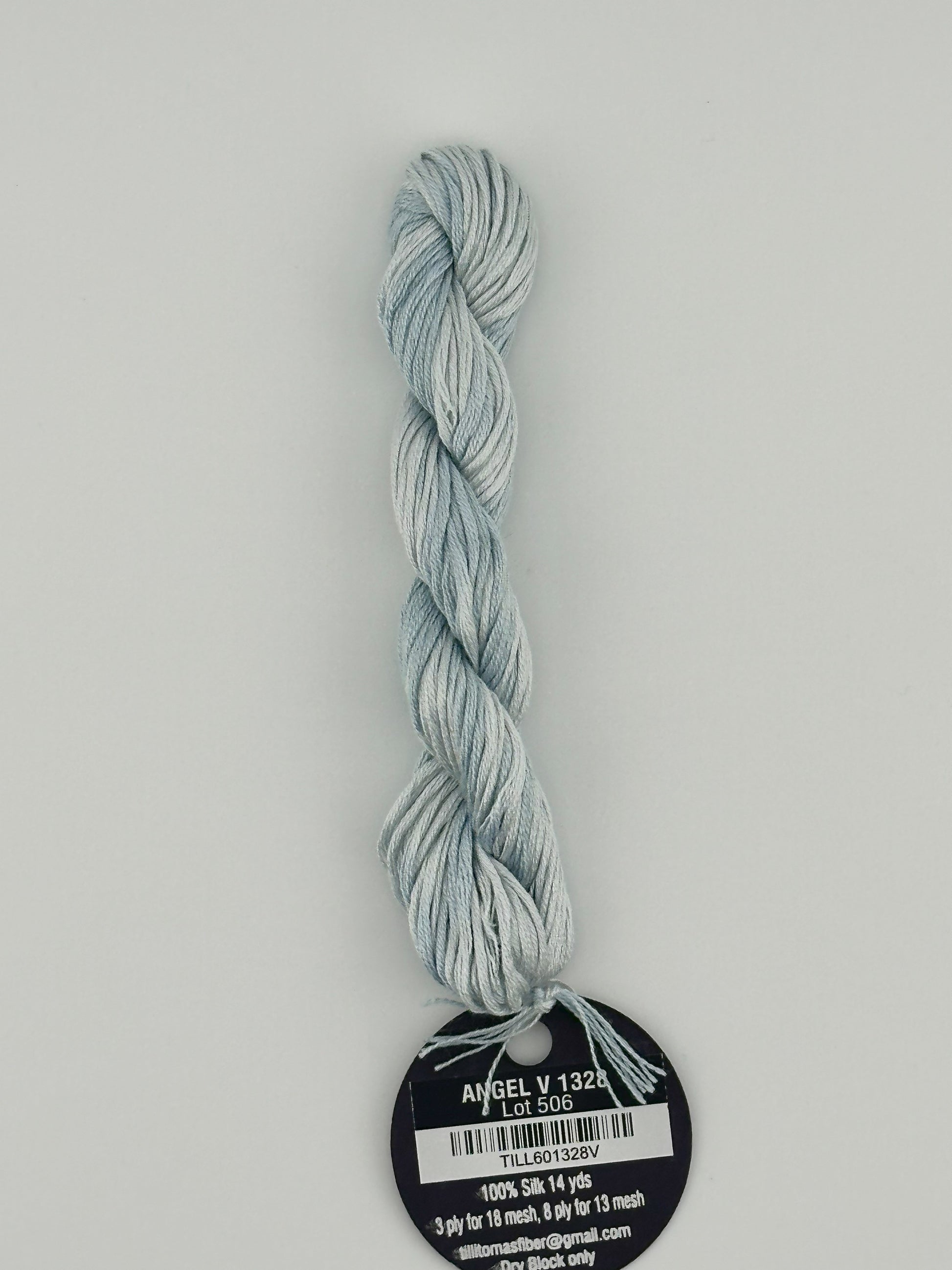 14 yard skein Planet Earth Silk 4 Ply needlepoint thread, in angel v 1328, with round black and white label lying flat on white background.