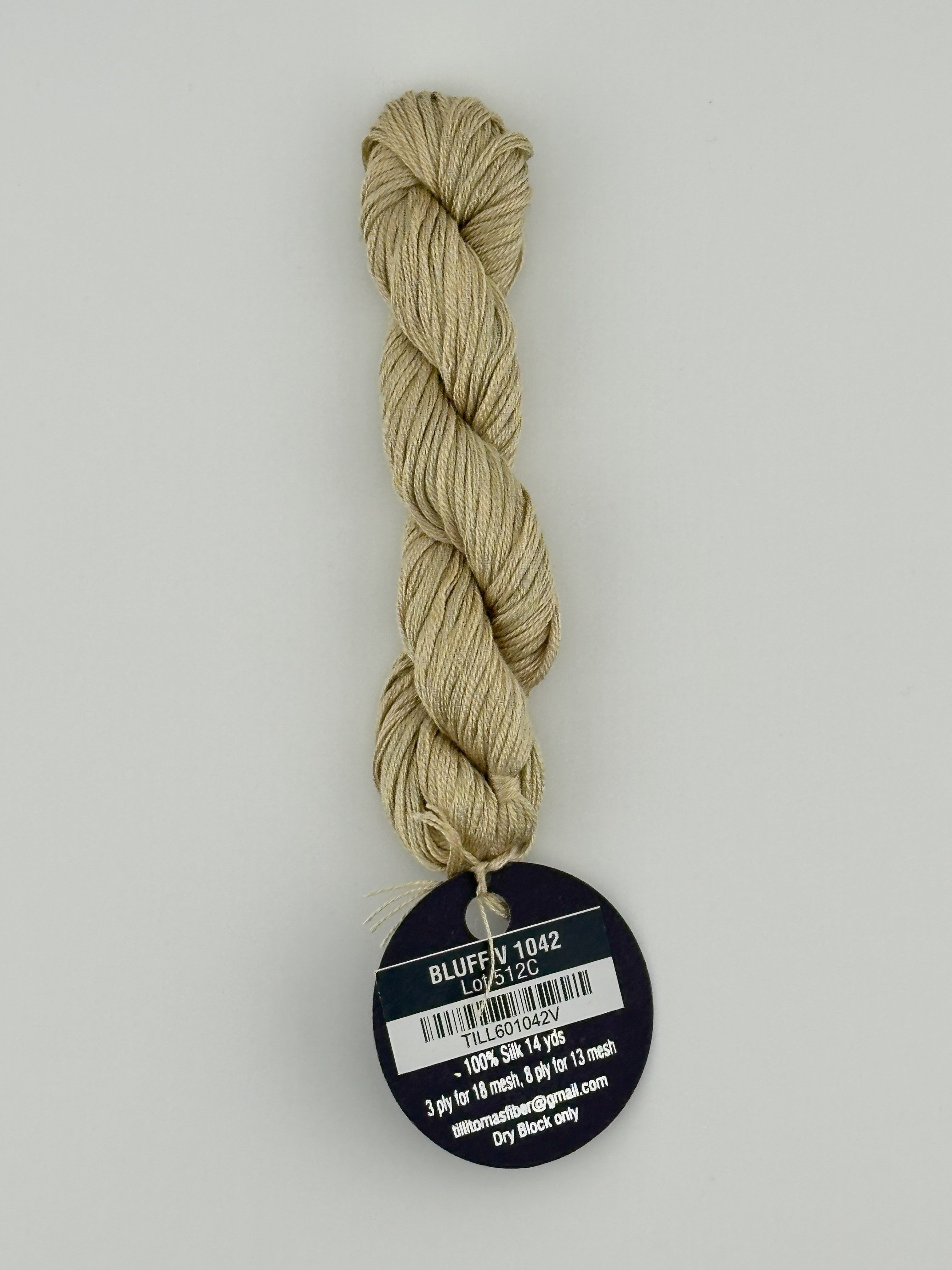 14 yard skein Planet Earth Silk 4 Ply needlepoint thread, in bluff v 1042, with round black and white label lying flat on white background.