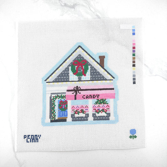 13 mesh needlepoint canvas featuring a Christmas candy store design, with a color swatch strip on the right and the brand name 'PENNY LINN' in the bottom left corner, displayed on a white marble surface.