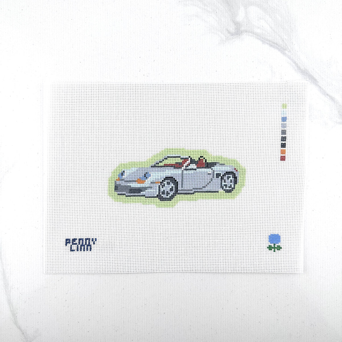 18 mesh needlepoint canvas featuring a silver Porsche convertible sports car with a green outline, the text 'PENNY LINN' in blue at bottom left, and a small blue hydrangea at bottom right, photographed on a white background.
