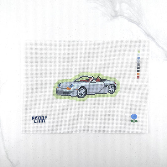 18 mesh needlepoint canvas featuring a silver Porsche convertible sports car with a green outline, the text 'PENNY LINN' in blue at bottom left, and a small blue hydrangea at bottom right, photographed on a white background.