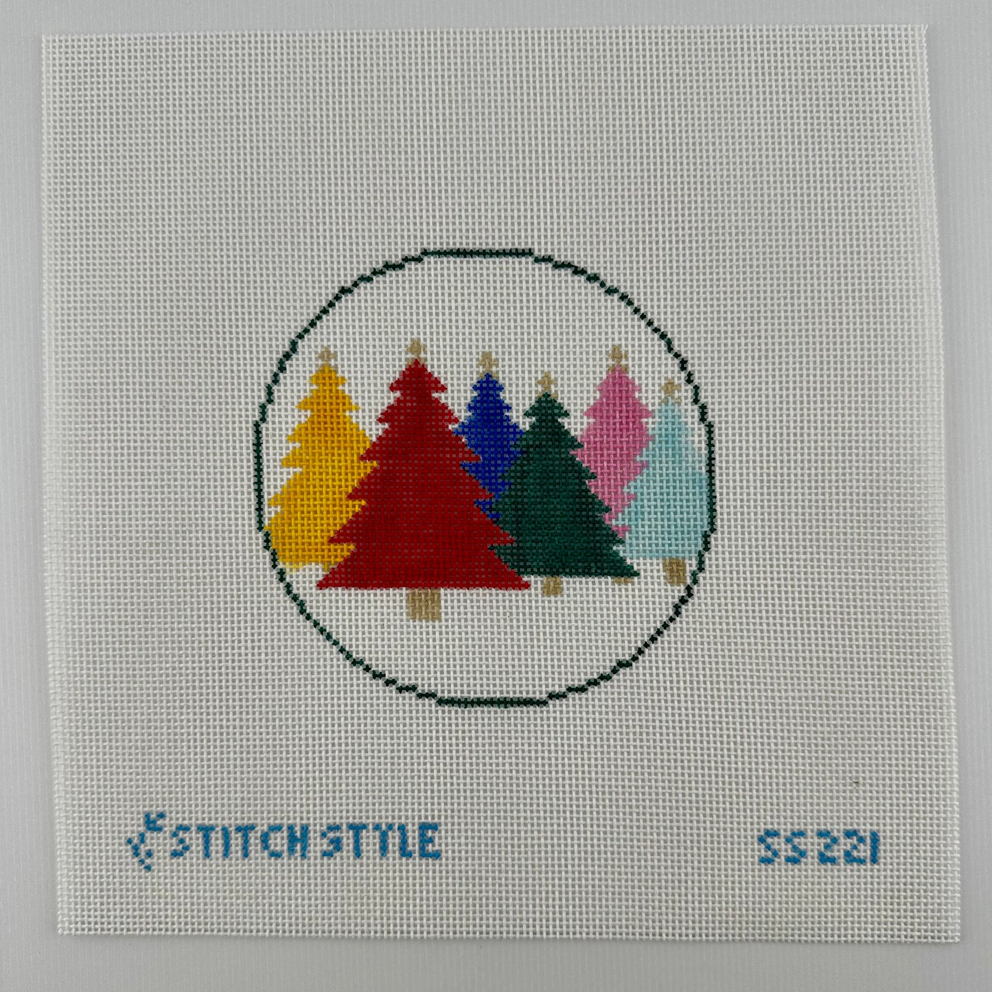 18 mesh needlepoint canvas featuring a circular design of six colorful Christmas trees in yellow, red, blue, green, pink, and light blue. The canvas has the brand name 'Stitch Style' and the number '55221' printed in blue at the bottom.