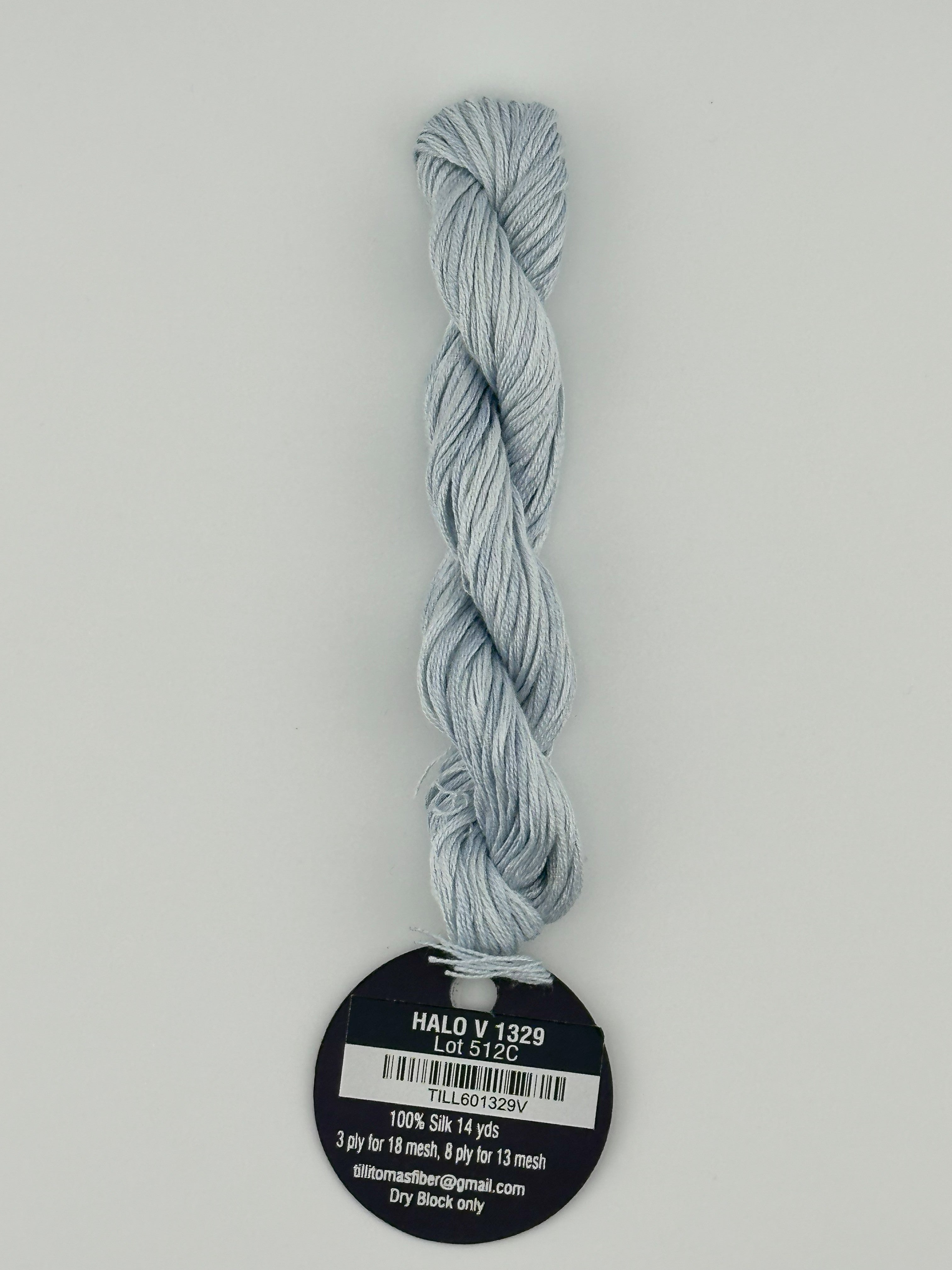 14 yard skein Planet Earth Silk 4 Ply needlepoint thread, in halo v 1329, light blue, with round black and white label lying flat on white background.