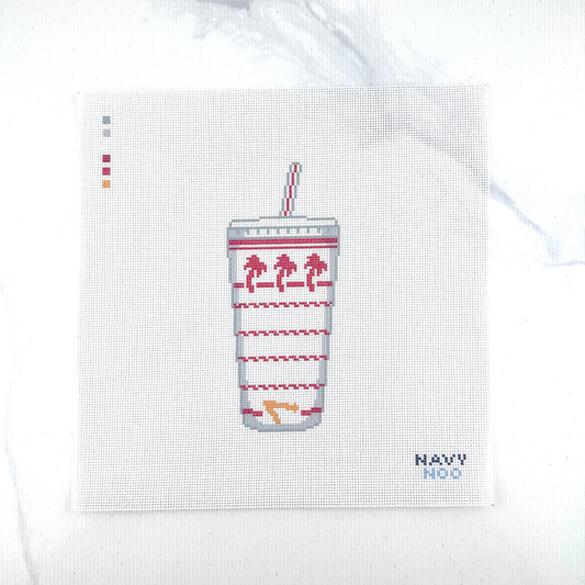 18 mesh needlepoint canvas design featuring a white paper cup with a red-and-white striped straw, palm tree motifs and red wavy line patterns . The canvas is photographed on a white marble-like surface, with the brand name 'NAVY NOO' printed in blue in the bottom right corner.