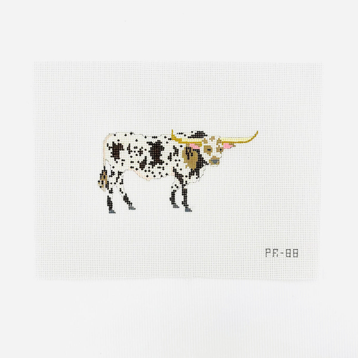 A needlepoint canvas featuring a brown and white spotted longhorn bull, displayed flat on a white background.