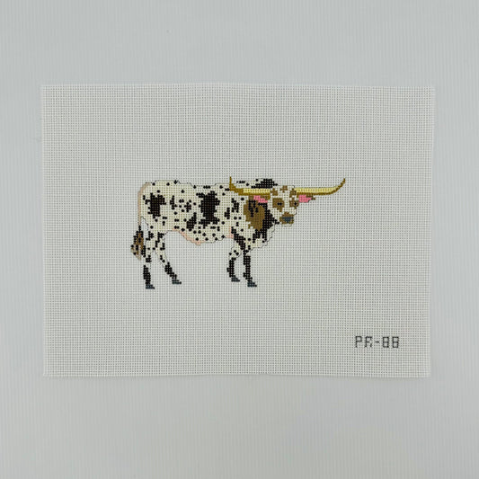 A needlepoint canvas featuring a brown and white spotted longhorn bull, displayed flat on a white background.