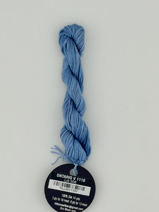 14 yard skein Planet Earth Silk 4 Ply needlepoint thread, in ontario v 1110, with round black and white label lying flat on white background.