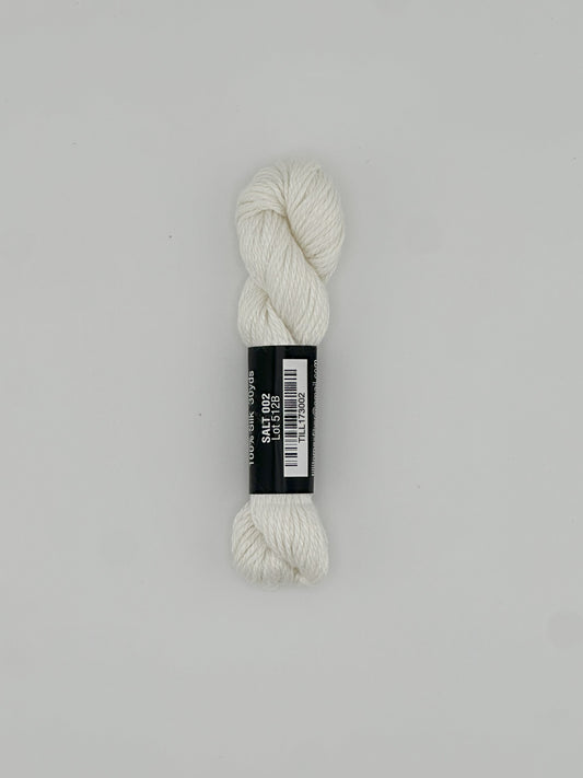 30 yard skein of Pepper Pot Silk needlepoint thread in salt 002 white, with black and white label lying flat on white background