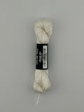 30 yard skein of Pepper Pot Silk needlepoint thread in cream 003, with black and white label lying flat on white background
