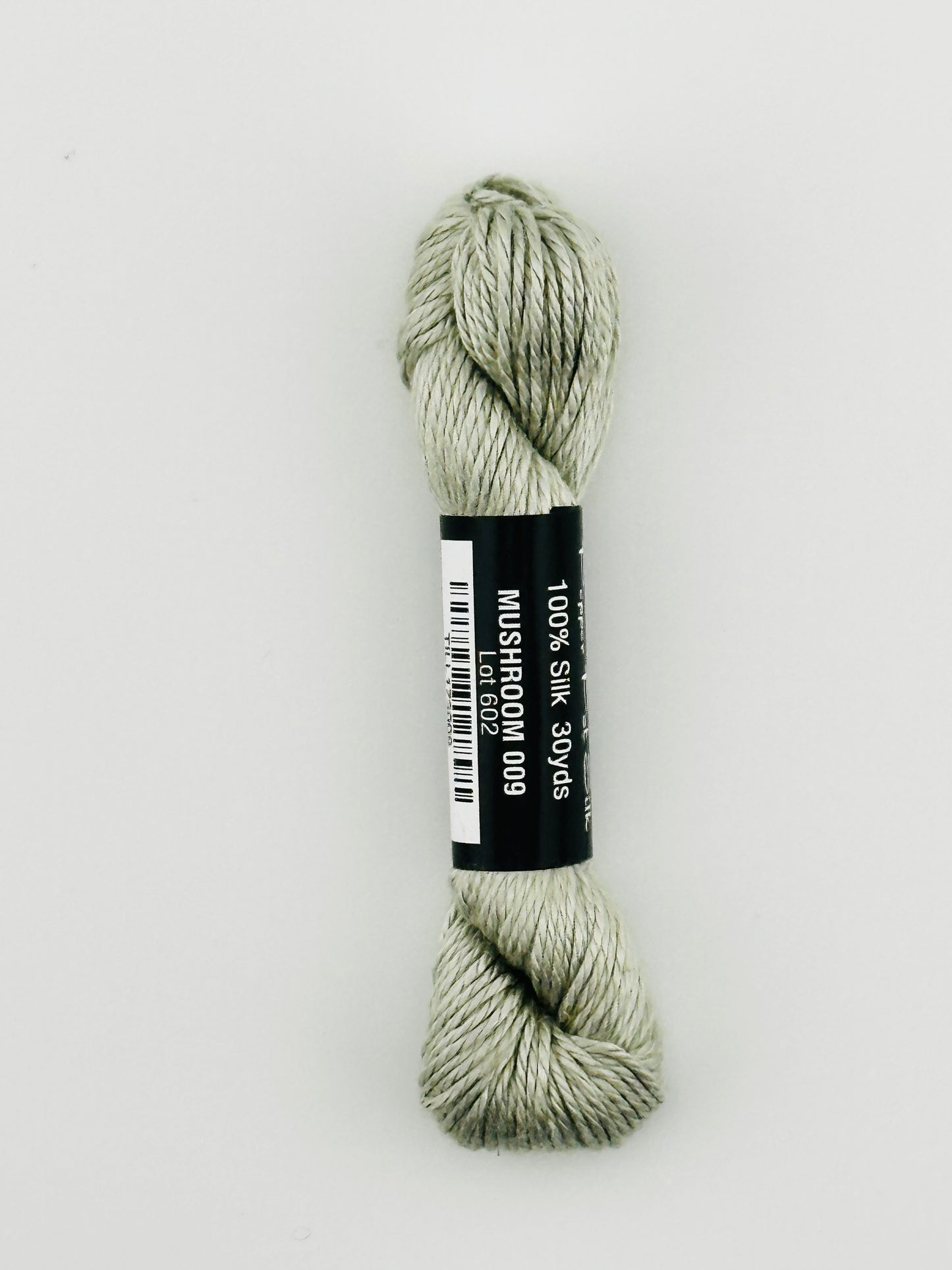 30 yard skein of Pepper Pot Silk needlepoint thread in mushroom 009, with black and white label lying flat on white background