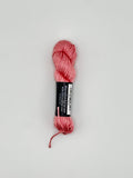 30 yard skein of Pepper Pot Silk needlepoint thread in strawberry frappe pink 014 with black and white label lying flat on white background