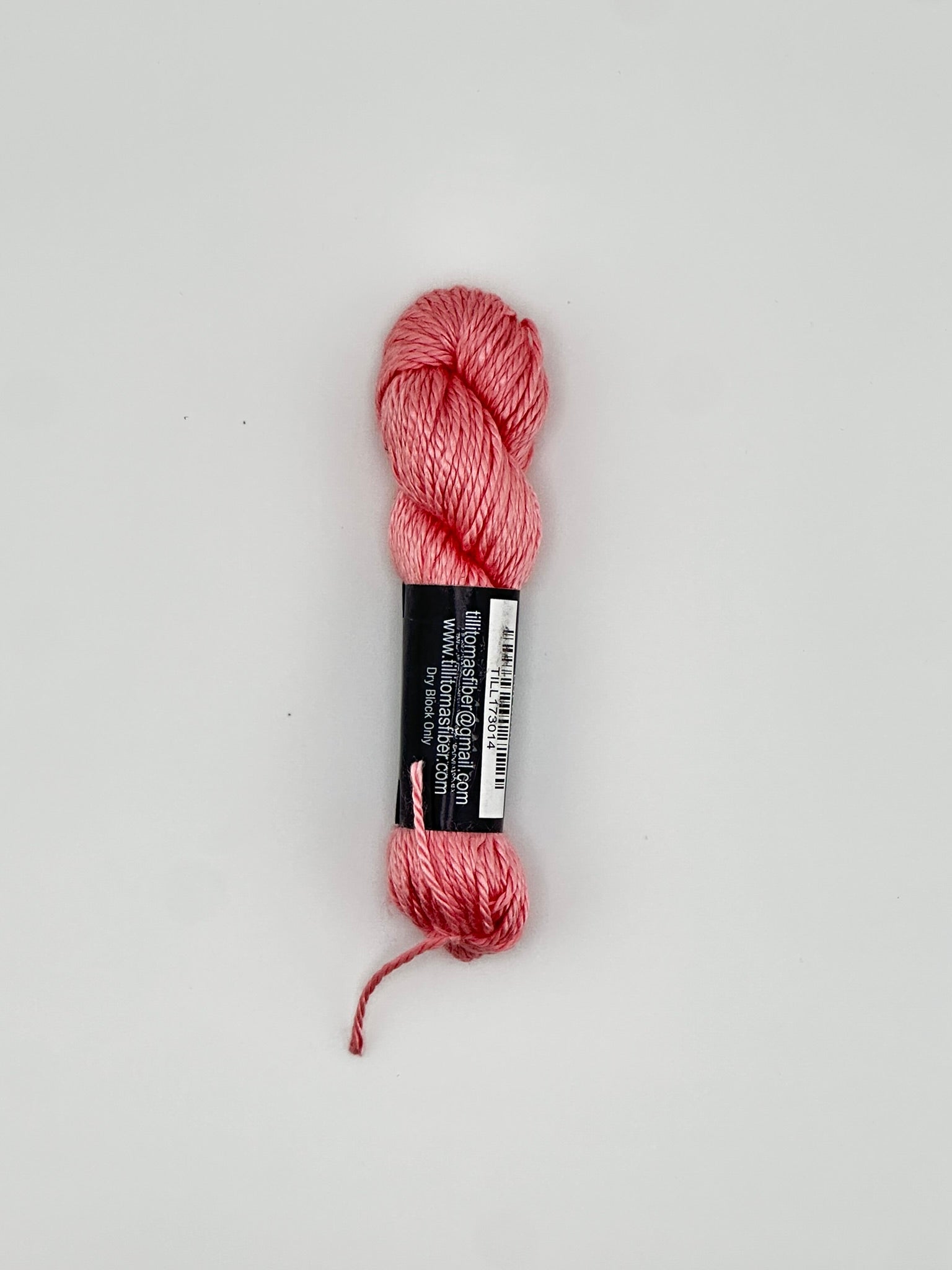 30 yard skein of Pepper Pot Silk needlepoint thread in strawberry frappe pink 014 with black and white label lying flat on white background