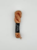 30 yard skein of Pepper Pot Silk needlepoint thread in callop 035 with black and white label lying flat on white background