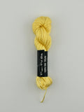 30 yard skein of Pepper Pot Silk needlepoint thread in popcorn 044 yellow, with black and white label lying flat on white background
