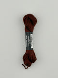 30 yard skein of Pepper Pot Silk needlepoint thread in root beer 055 brown, with black and white label lying flat on white background