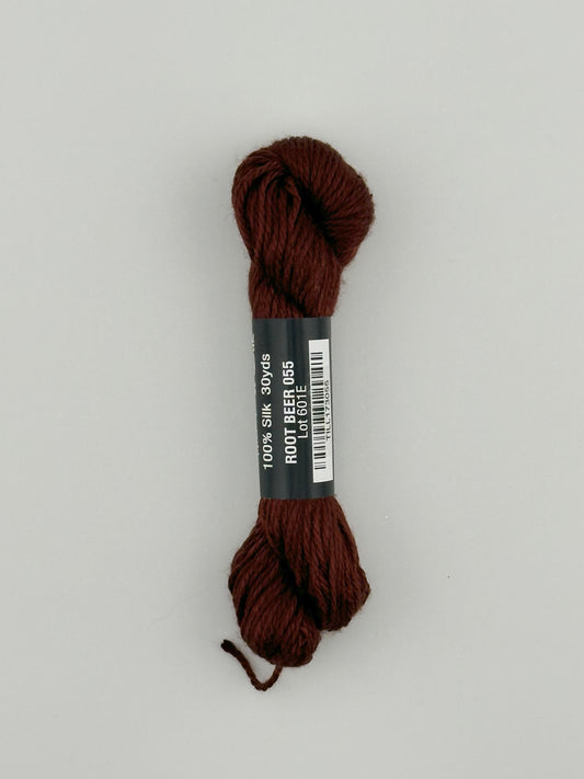 30 yard skein of Pepper Pot Silk needlepoint thread in root beer 055 brown, with black and white label lying flat on white background