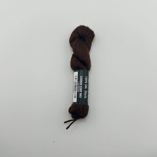 30 yard skein of Pepper Pot Silk needlepoint thread in cookie chip 063 brown with black and white label lying flat on white background