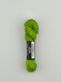 30 yard skein of Pepper Pot Silk needlepoint thread in Kiwi 083 green, with black and white label lying flat on white background