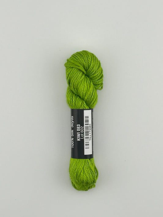 30 yard skein of Pepper Pot Silk needlepoint thread in Kiwi 083 green, with black and white label lying flat on white background