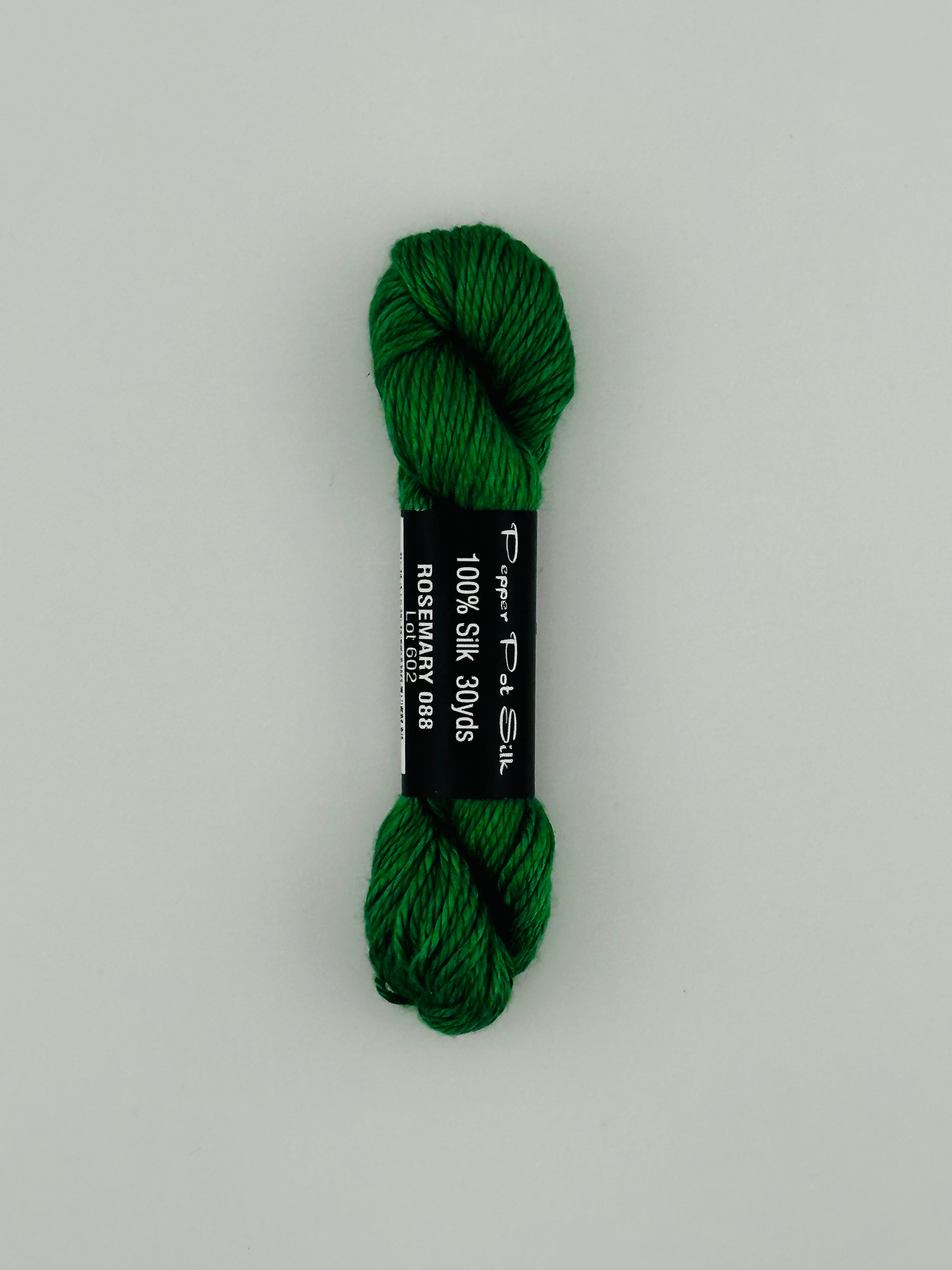 30 yard skein of Pepper Pot Silk needlepoint thread in rosemary 088, with black and white label lying flat on white background