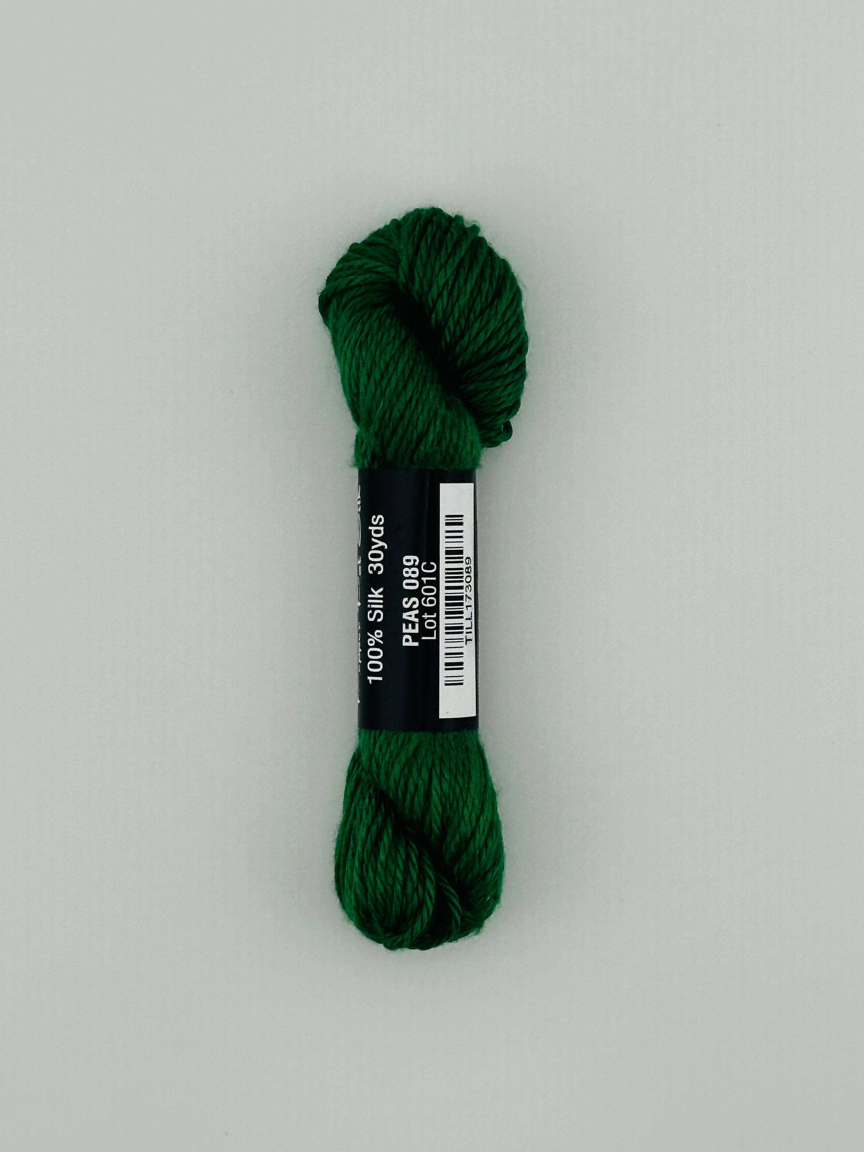 30 yard skein of Pepper Pot Silk needlepoint thread in peas 089, with black and white label lying flat on white background