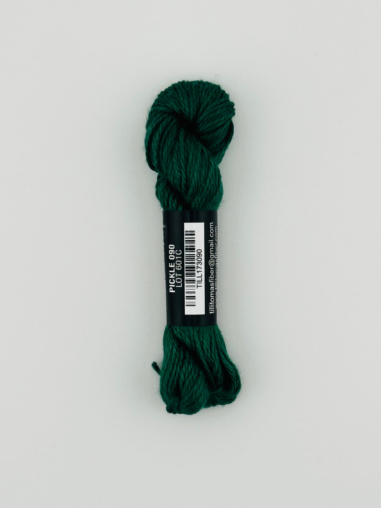30 yard skein of Pepper Pot Silk needlepoint thread in pickle 090, with black and white label lying flat on white background