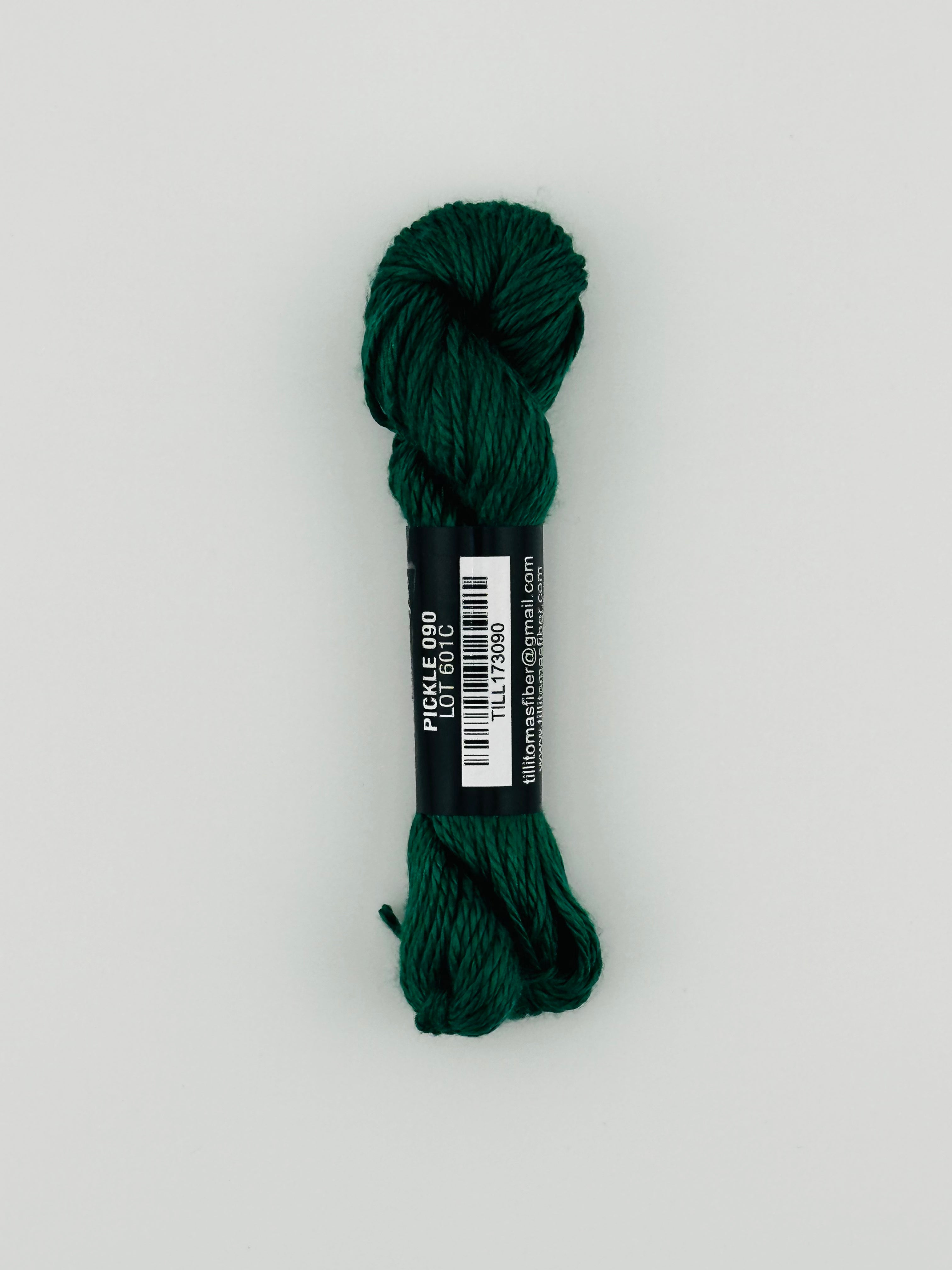 30 yard skein of Pepper Pot Silk needlepoint thread in pickle 090, with black and white label lying flat on white background