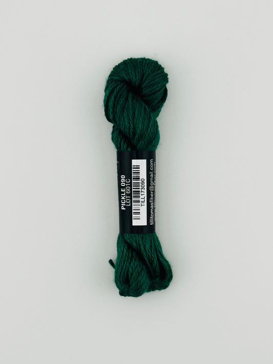 30 yard skein of Pepper Pot Silk needlepoint thread in pickle 090, with black and white label lying flat on white background