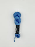 30 yard skein of Pepper Pot Silk needlepoint thread in water blue 112 with black and white label lying flat on white background