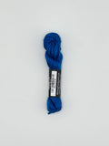30 yard skein of Pepper Pot Silk needlepoint thread in marine blue 115 with black and white label lying flat on white background