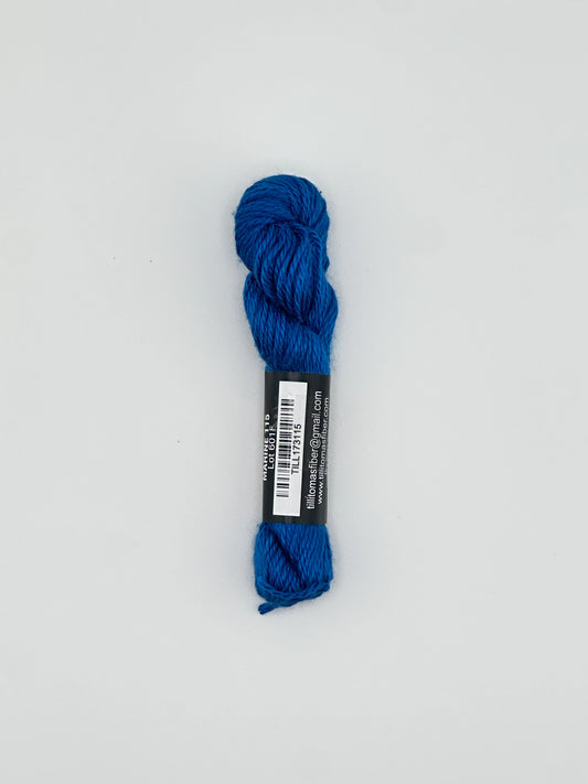 30 yard skein of Pepper Pot Silk needlepoint thread in marine blue 115 with black and white label lying flat on white background