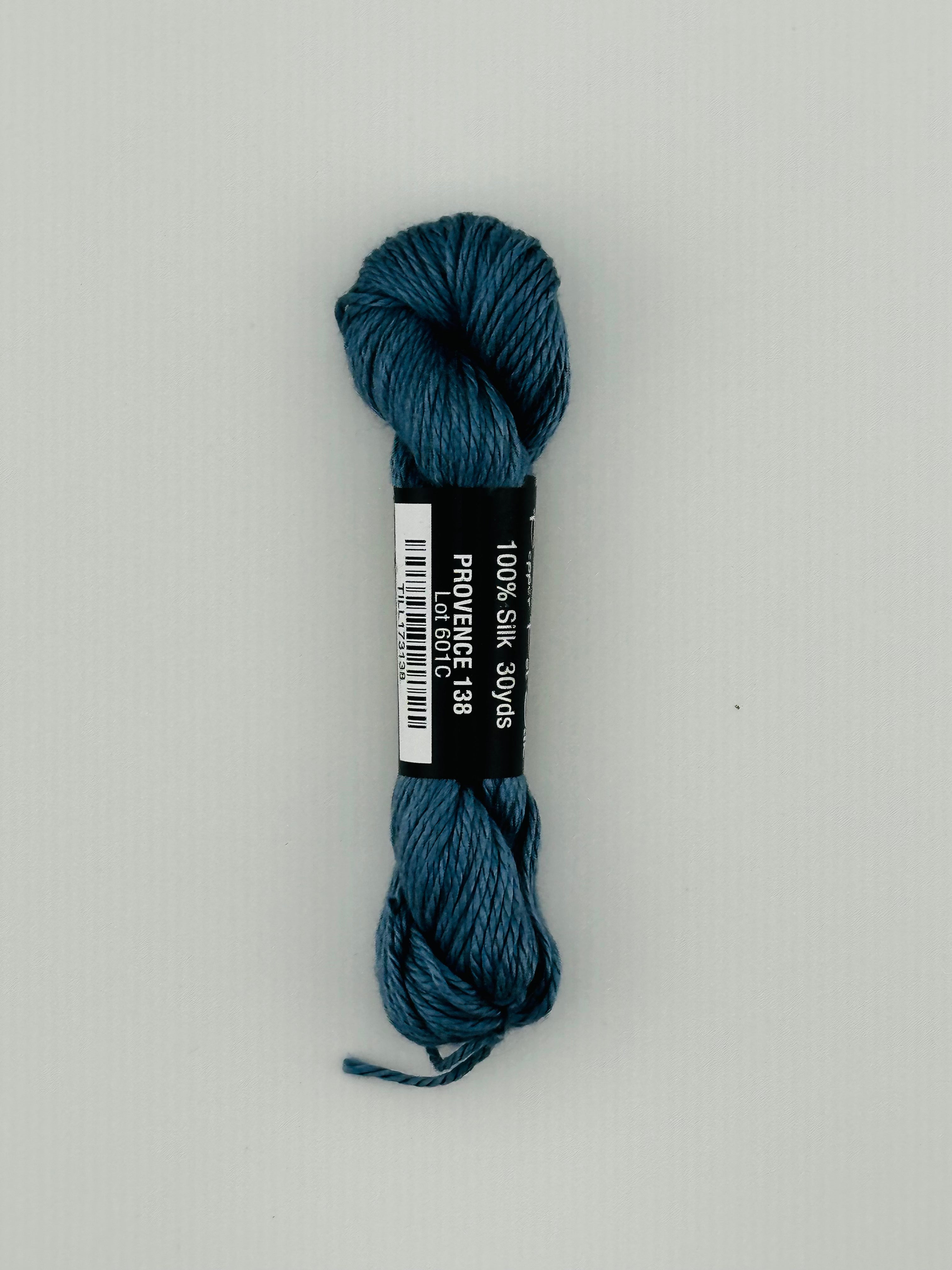 30 yard skein of Pepper Pot Silk needlepoint thread in provence 138, with black and white label lying flat on white background
