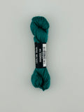 30 yard skein of Pepper Pot Silk needlepoint thread in seaweed 154, with black and white label lying flat on white background
