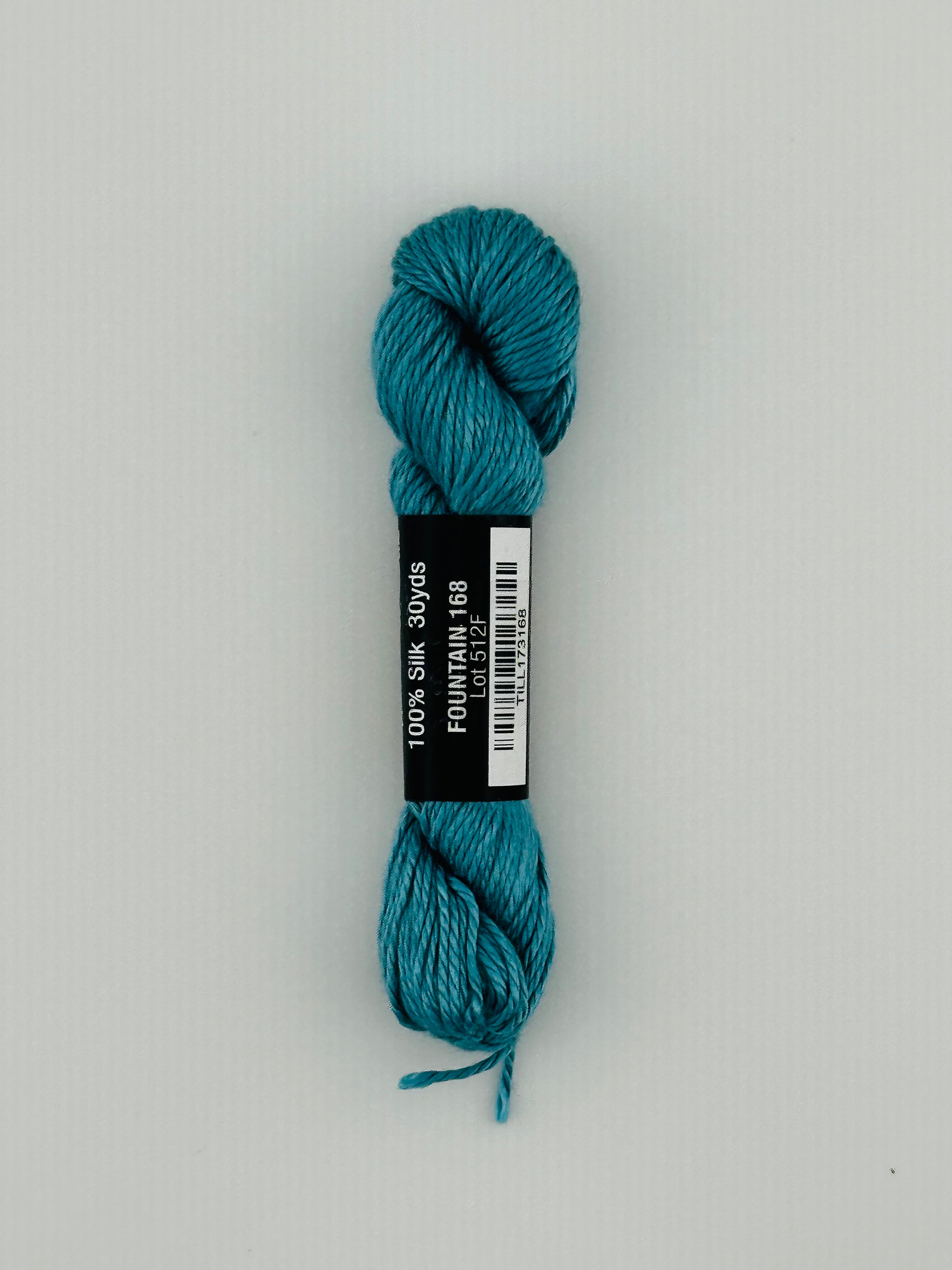 30 yard skein of Pepper Pot Silk needlepoint thread in fountain 168, with black and white label lying flat on white background