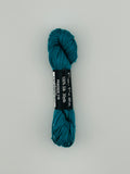 30 yard skein of Pepper Pot Silk needlepoint thread in peacock 178, with black and white label lying flat on white background