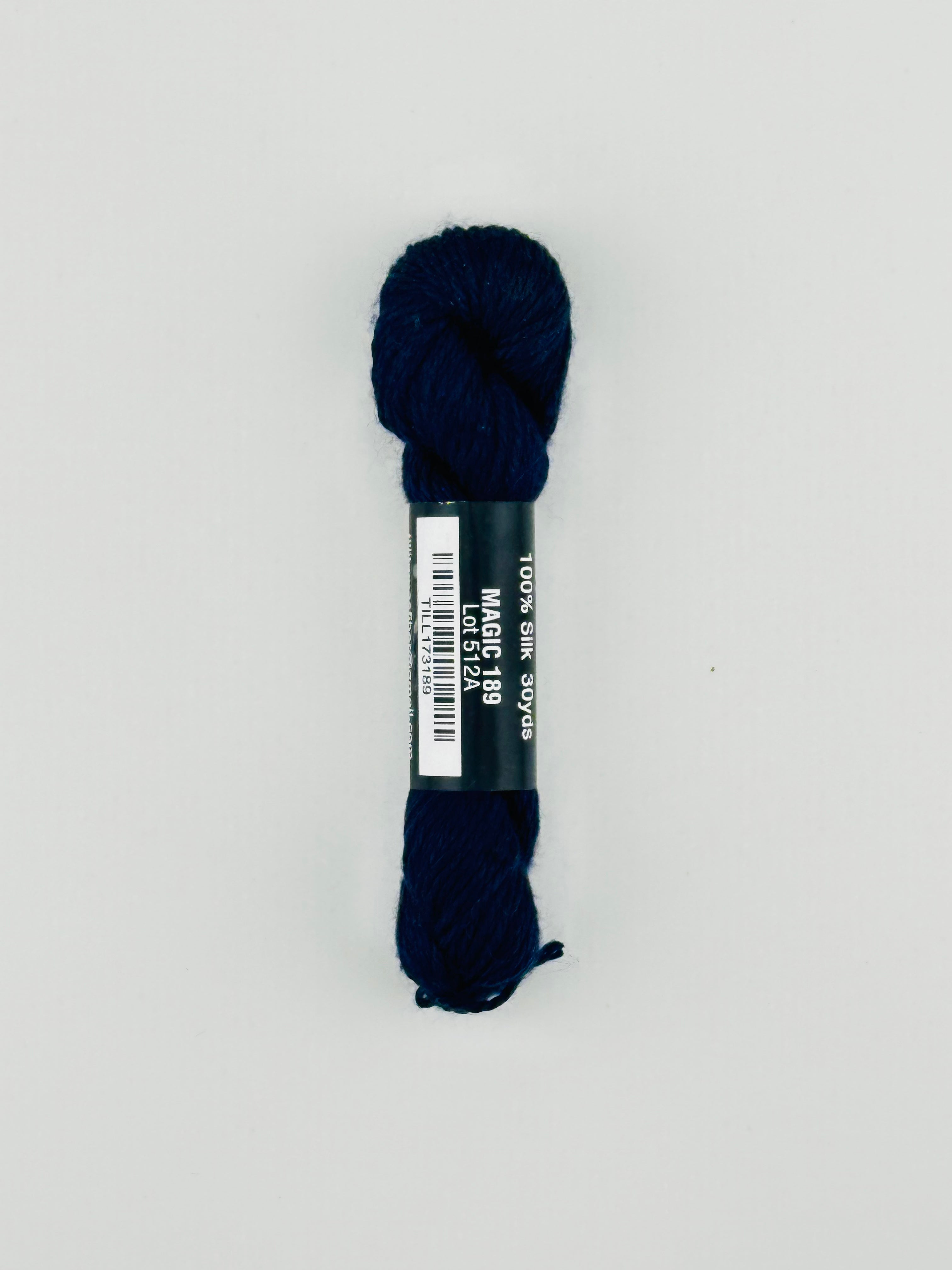 30 yard skein of Pepper Pot Silk needlepoint thread in magic 189, with black and white label lying flat on white background