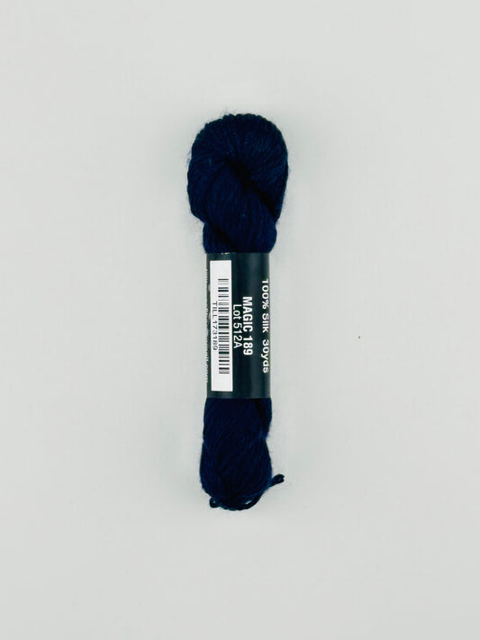 30 yard skein of Pepper Pot Silk needlepoint thread in magic 189, with black and white label lying flat on white background