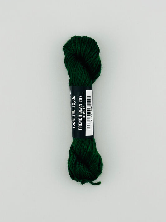 30 yard skein of Pepper Pot Silk needlepoint thread in french bean 207 green, with black and white label lying flat on white background