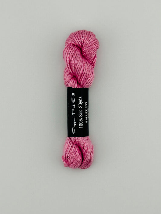 30 yard skein of Pepper Pot Silk needlepoint thread in ballet 237, with black and white label lying flat on white background