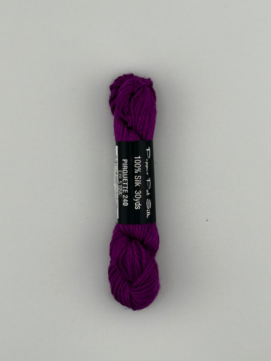 30 yard skein of Pepper Pot Silk needlepoint thread in piroutte 240, with black and white label lying flat on white background