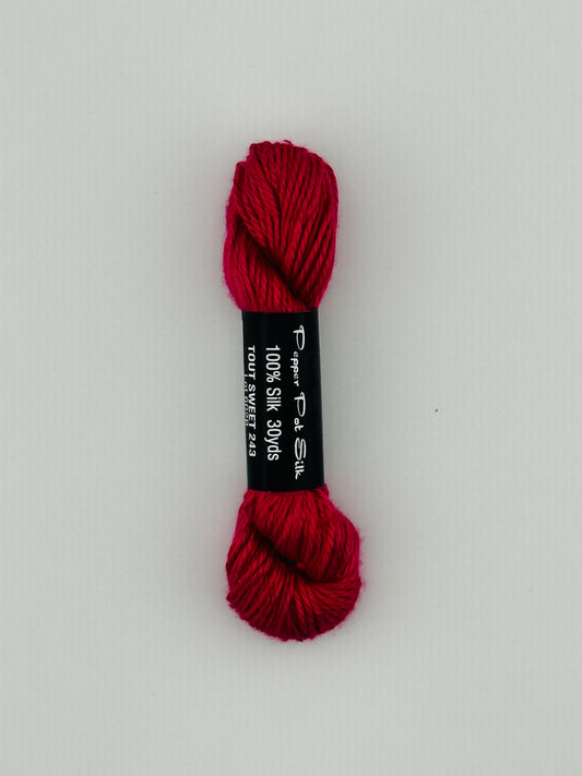 30 yard skein of Pepper Pot Silk needlepoint thread in tout sweet 243, with black and white label lying flat on white background