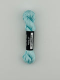 30 yard skein of Pepper Pot Silk needlepoint thread in breeze 247, with black and white label lying flat on white background