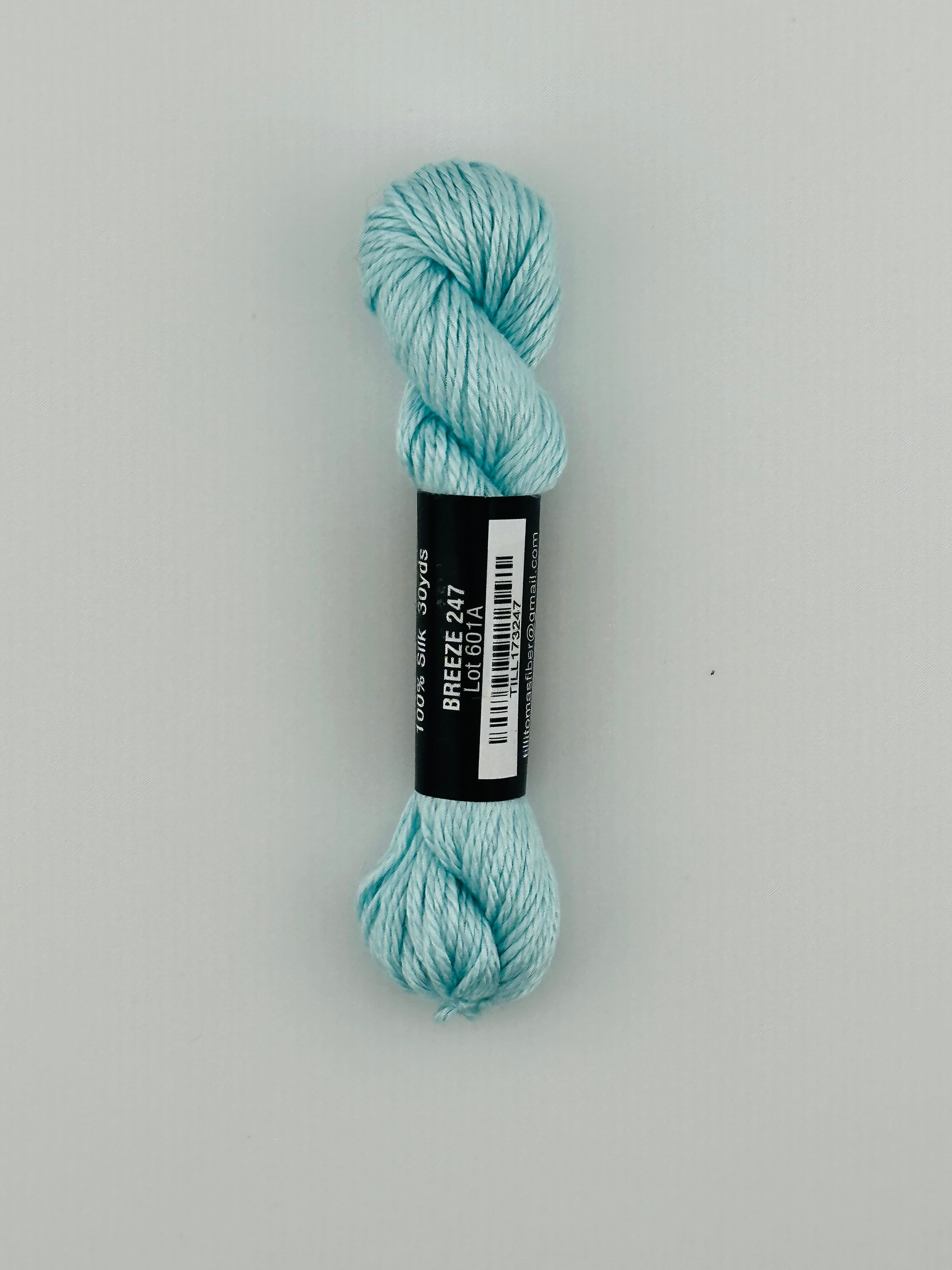 30 yard skein of Pepper Pot Silk needlepoint thread in breeze 247, with black and white label lying flat on white background